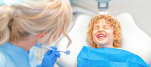 Pretty little boy in dental office, having his teeth checked by female dentist